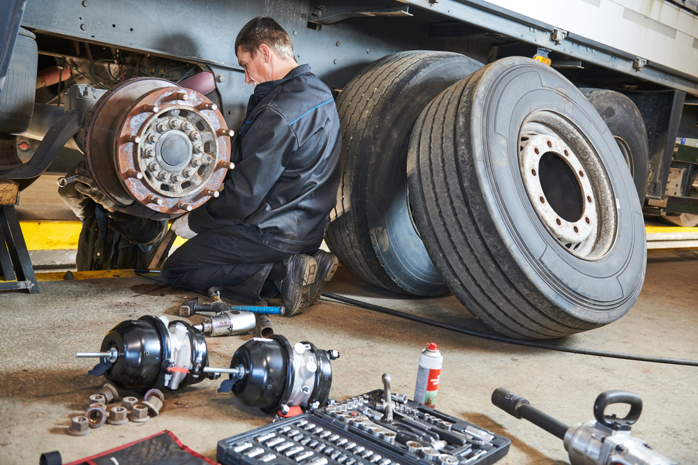 Truck repair service. Mechanic takes off tyre for brake replacement